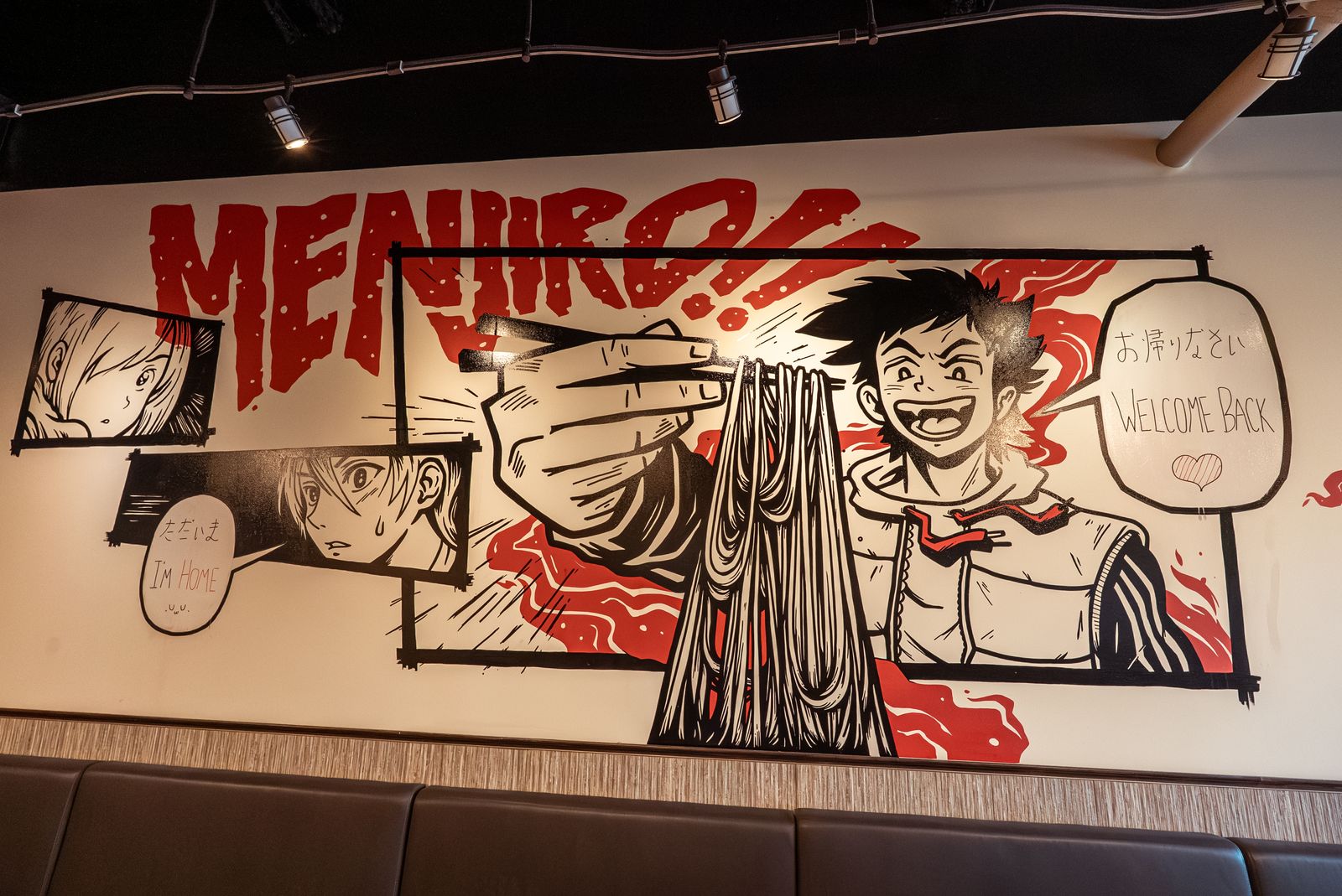 The manga mural inside Menjiro Ramen, with a cook lifting noodles and the words Welcome back